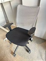 Front view of office chair showing mesh back, seat, armrests and casters