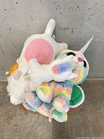 Box containing rainbow caticorn, white cat, turtle and orange plush