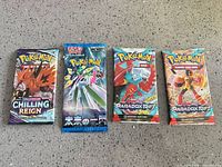 Four sealed Pokémon booster packs arranged side by side