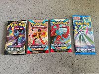All four sealed Pokémon booster packs laid out on countertop