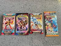 All four sealed Pokémon booster packs lined up on countertop