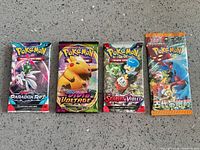 Four sealed Pokémon TCG booster packs laid flat
