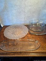 Three glass trays on table: fish platter, round frosted tray, octagonal dish