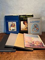 Group shot of seven hardcover books standing and lying flat