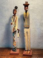 Front view of both carved wood figurines standing on bases