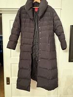 Front view of full-length dark brown quilted puffer coat on hanger