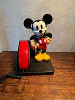 Front view of Mickey Mouse telephone showing figure, red handset, black base and cord