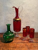 Group shot showing red decanter, four red cordial glasses, green vase