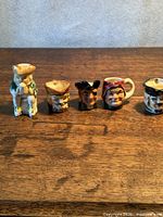 Group shot of five Toby jugs lined up on wooden surface
