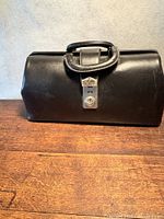 front view of black leather doctor’s bag showing clasp and handle
