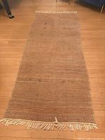 Full view of rectangular woven leather rug on wood floor