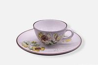 Teacup on saucer showing floral design and brown rim