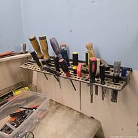 Perforated rail holding various screwdrivers, pliers visible in bin below