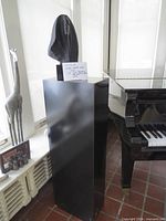 Full view of sculpture on pedestal beside piano