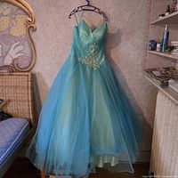 Front view of aqua Venus gown on hanger showing bodice, straps, appliqué and full tulle skirt