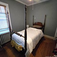Full view of twin four-poster bed against wall showing headboard, footboard and posts