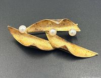 Front view of brooch showing leaf design and three pearls