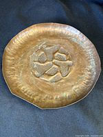 Front view of round hammered copper tray showing decorative center and hammered rim