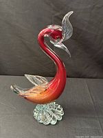 Front view of cranberry glass pelican showing color gradient, clear wings, footed base