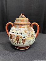 Front view of eggshell porcelain Satsuma style sugar bowl showing decoration, handles and lid