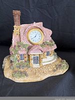 Front view of resin cottage figurine featuring built-in clock