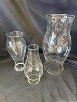 Three clear glass hurricane chimneys grouped