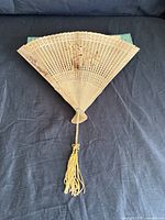 Fan fully opened showing carved lattice design and tassel