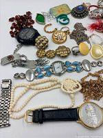 Overview of assorted watches, brooches, chains and earrings