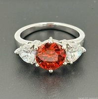 Top view of ring showing orange sapphire and two clear pear stones