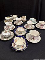 Group of assorted floral teacup and saucer sets with creamer