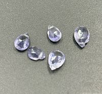 Five loose violet-blue faceted tanzanite stones on black background