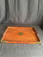 Top view showing wood grain, brass corners, side handles, circular brass inlay