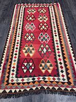 Full view of red ground kilim rug with geometric borders