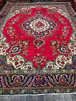 Full view of rug showing red field, central medallion, borders