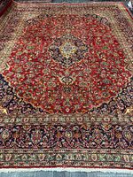 Full view of Kashan rug showing red field, central medallion, borders, fringe