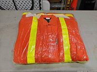 Folded orange insulated coverall with reflective stripes sealed in plastic