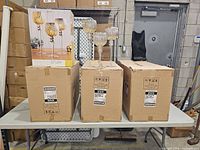 Three shipping cartons with one retail box and a displayed set of three candle holders on top