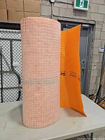 Full roll standing on table with leading edge unrolled showing underside grid