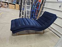 Side view of navy blue velvet chaise lounge showing curved profile and gold metal base