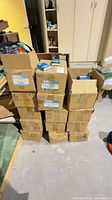 Stack of fourteen cardboard shipping boxes on floor