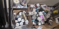 Two boxes filled with numerous spray paint cans on the floor