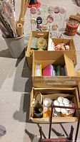 Three cartons containing craft items, ribbon rack in background