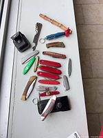 Group shot of all knives, lighter case, bottle openers, sheaths