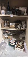 Full cabinet view with assorted ceramic planters, vases, candlesticks, angels, plant stand, glass lamp base and misc decor