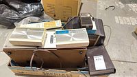 Multiple vintage radios and tape equipment stacked in box