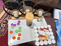 Group view of all items: tealights pack, pillar candle, wood base triple votive holder, multicolor magnetic discs, metal clips