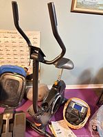 Partially assembled bike frame showing handlebars, saddle, flywheel housing and adjoining components