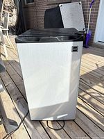 Front view of RCA mini fridge showing stainless-look door and power cord
