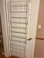 full view of white plastic shoe rack hanging on door