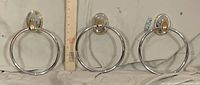 Three metal towel rings shown side by side with ruler for scale
